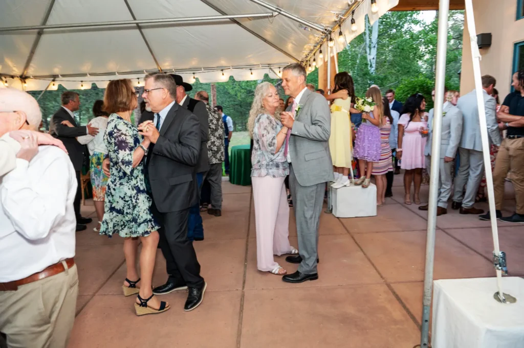 Dancing under a tent with lights at an outdoor wedding